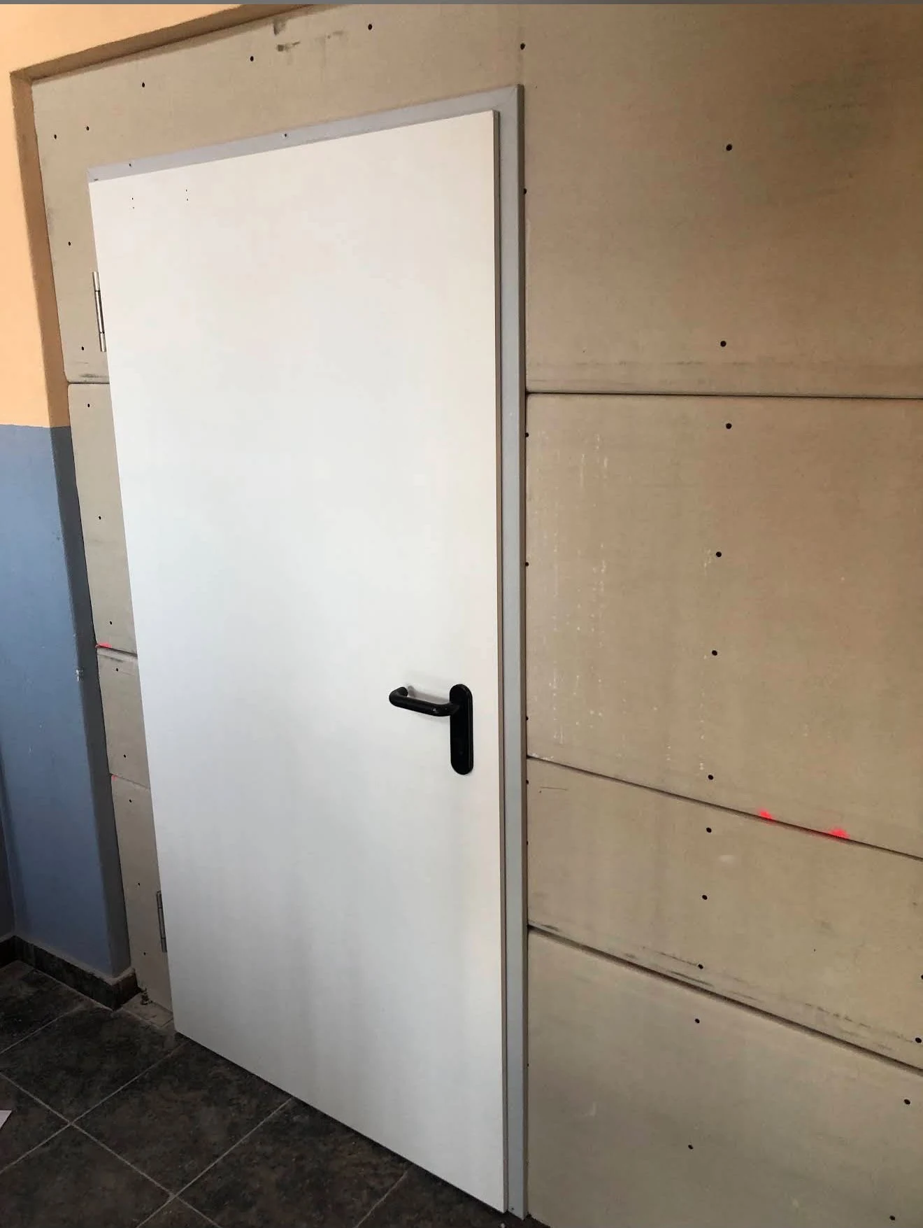 Weiße Tür in einer mit Bauplatten verkleideten Wand
